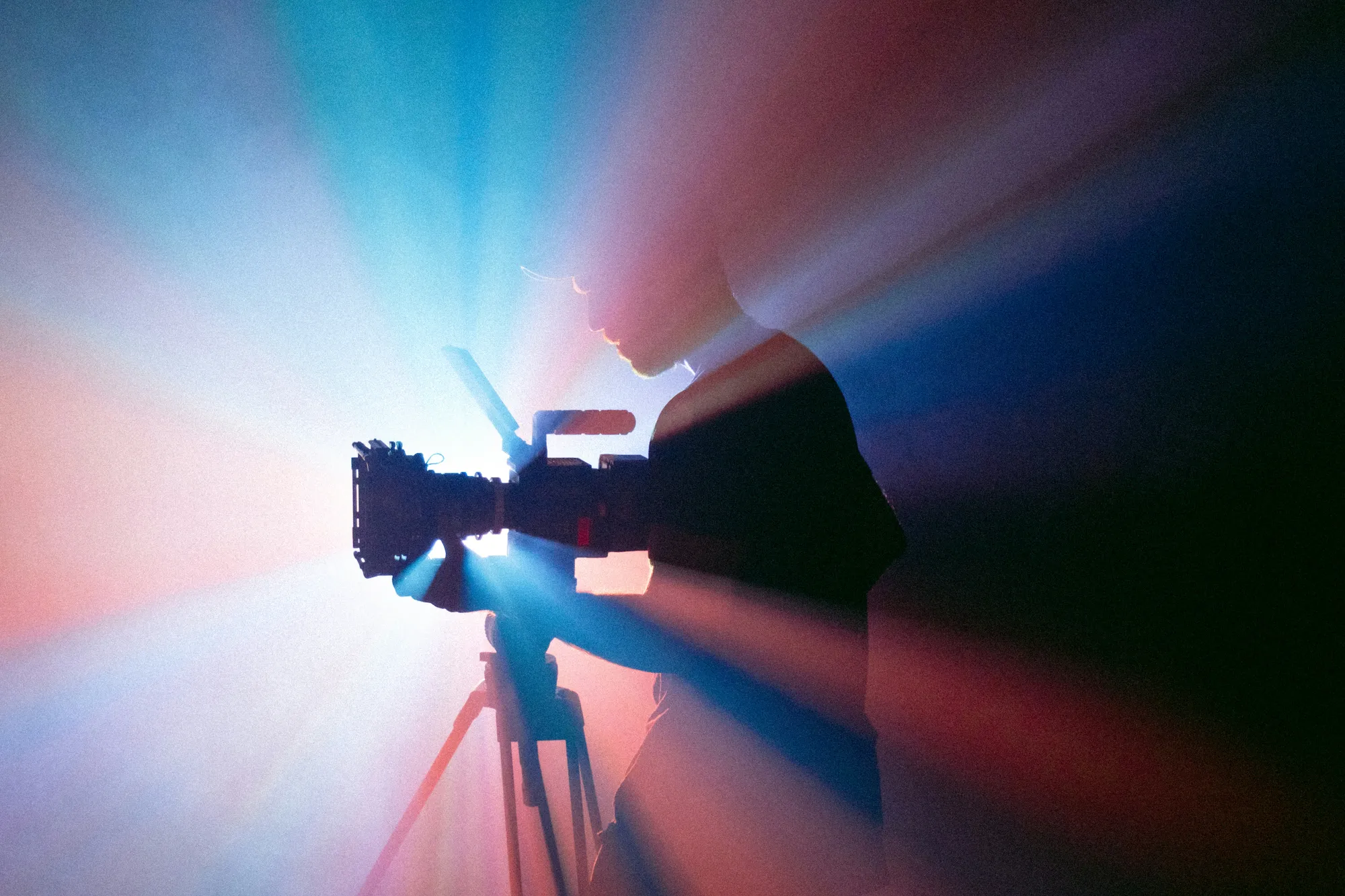 Silhouetted camera operator backlit by coloured light rays on set